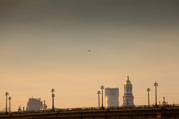 Fototapeta na wymiar View of the big city over bridge in awesome bright sunset. Domes of cathedrals and churches of the Kiev-Pechersk Lavra. Kyiv. Ukraine.