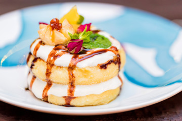 Cottage cheese pancakes or syrniki with cream, fruit jam and flower decoration