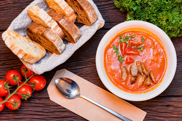 Plate with freshly cooked tomato soup with sausage served with bread
