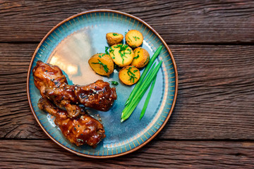 Top view roasted chicken quarter legs with baked potato on rustic background
