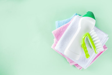 Spring home cleaning and housekeeping concept, Basket with cleaning items, utensils, supplies. Copy space over green background with spring blossom flowers