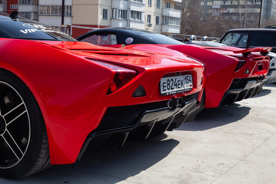Two Cars Marussia Motors Model B1 In Red Color And Black Roof And Wheels Rear View. Photography Of A Russian Supercar Near The Dealership On Parking