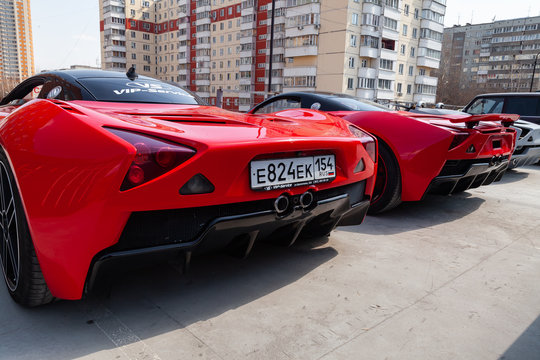 Two Cars Marussia Motors Model B1 In Red Color And Black Roof And Wheels Rear View. Photography Of A Russian Supercar Near The Dealership On Parking