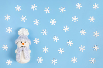Christmas composition with white snowflakes and a cute snowman on a pastel blue background. Winter...