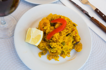 Paella with shrimp, pepper, vegetables and lemon on platter