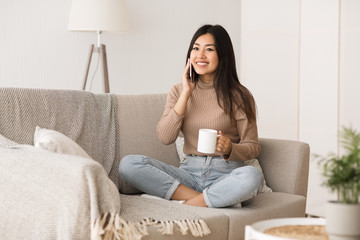 Teen girl calling on mobile, sitting on couch in living room