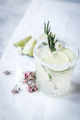 making cocktails in glasses with lime and herbs on stone kitchen desk background