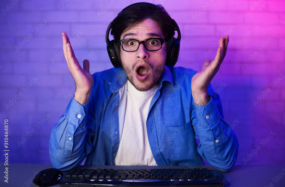 Poster surprised gamer with headset playing video games on computer