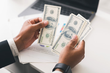 Cropped of businessman counting dollar banknotes at workplace