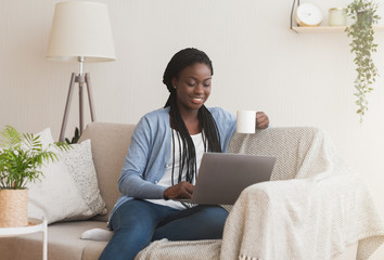 Black Girl Watching Movie On Laptop And Drinking Coffee On Couch