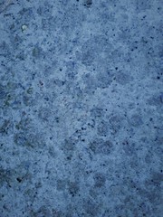 close-up of a decorative wall with bokeh effect and characteristic rough porous texture, abstract dark and light spots on a classic blue background