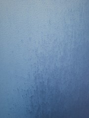 close-up of a decorative wall with bokeh effect and characteristic rough porous texture, abstract dark and light spots on a classic blue background