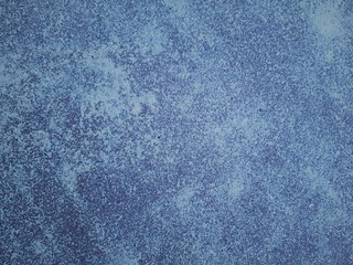 close-up of a decorative wall with bokeh effect and characteristic rough porous texture, abstract dark and light spots on a classic blue background