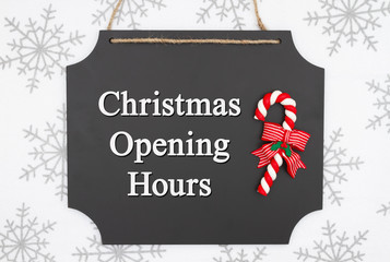 Christmas opening hours message on hanging chalkboard with a candy cane