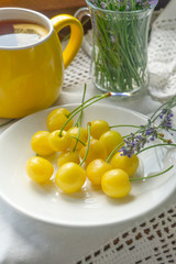 Fresh yellow cherries with fragrant flowers. Romantic breakfast.