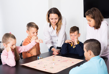 Fototapeta premium Elementary age friendly children at table with board game and dice