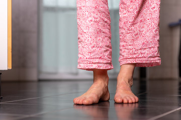 Woman is standing on the tile with bare feet
