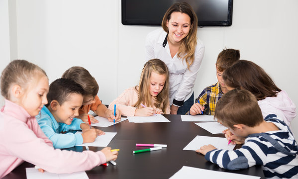 serious little children with teacher drawing in classroom