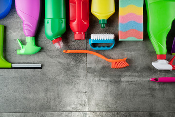 House cleaning concept. Top view of colorful cleaning products on gray tile floor.