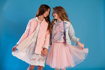 Portrait of two beautiful fashionable girl girlfriends in white pink dresses