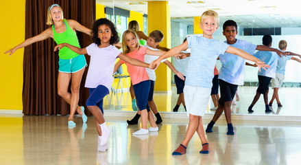 Group of children practicing vigorous jive movements in dance cl