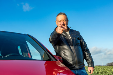 Man is standing next to his car and pointing his finger