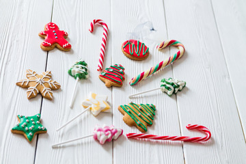 traditional Christmas sweets on white wooden background. Candy cane, round snowflake and ginger man, star lollipop. Top view. Flat lay. Christmas concept