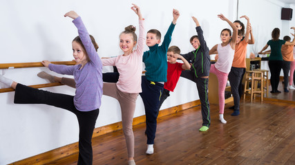 Fototapeta na wymiar friendly children rehearsing ballet dance in studio