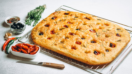 Traditional Italian Focaccia with tomatoes, olives and rosemary - homemade flat bread focaccia.