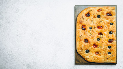 Traditional Italian Focaccia with tomatoes, olives and rosemary - homemade flat bread focaccia.