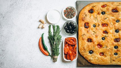 Traditional Italian Focaccia with tomatoes, olives and rosemary - homemade flat bread focaccia.