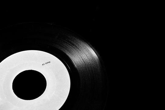 close up of 45 rpm vinyl disk on dark background