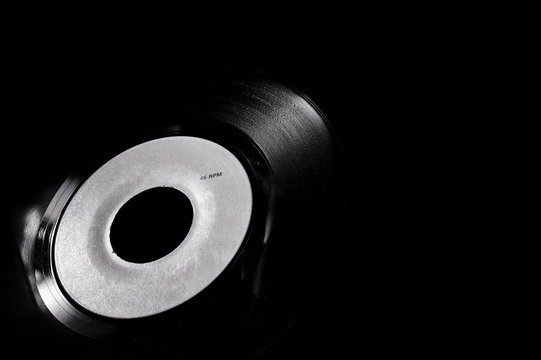 detail of 45 rpm vinyl disk on dark background