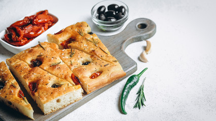 Traditional Italian Focaccia with tomatoes, olives and rosemary - homemade flat bread focaccia.