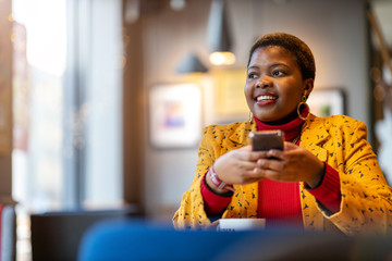 Happy young woman with smartphone in a cafe