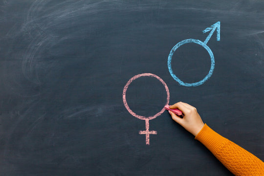 Gender symbols or signs for the male and female sex drawn on a blackboard