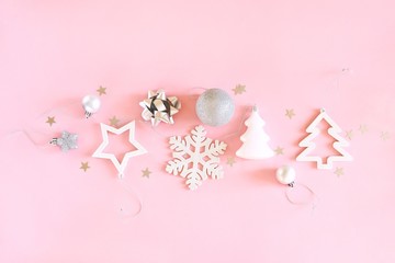 Christmas composition of white and silver decorations on a pastel pink background. Minimalistic holiday concept. Top view, flat lay.