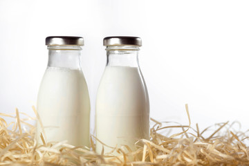 Bottles of fresh milk in the hay isolated on white. Close-up.