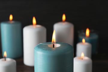 Fototapeta na wymiar Burning candles on dark wooden background, close up