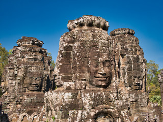 Fototapeta na wymiar Giant stone faces in temple ruins at the ancient Khmer site of Angkor Thom near Siem Reap in Cambodia.