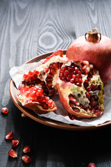 close-up, ripe pomegranates on a brown ceramic bowl on a black wooden table