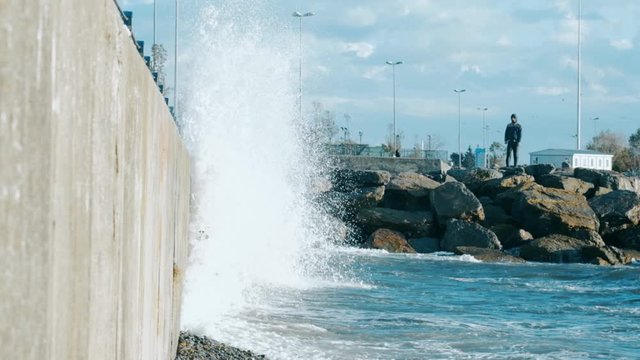 Man watching slow motion waves crashing over seawall at daytime in Istanbul