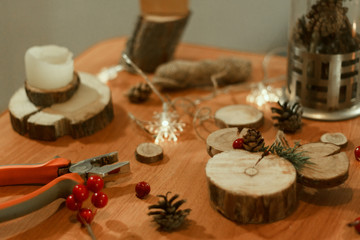  Creating a wooden Christmas decor in the form of a mouse on a table on which there are candles, scissors, a bump, threads, pliers, spruce branches, red berries and a garland of snowflakes