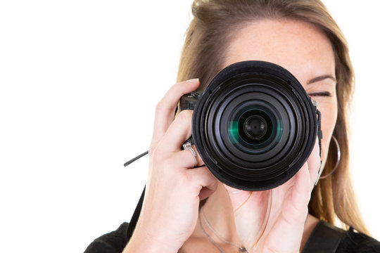 Young blonde photographer is taking a photo isolated on white background with copy space aside black camera lens