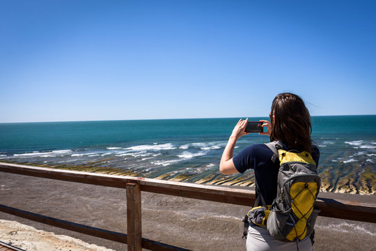 Rear view of a woman taking photos of atlantic ocean in Peninsula Valdes, Patagonia, Argentina