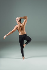 Obraz premium back view of dancer in black leggings dancing contemporary on dark background