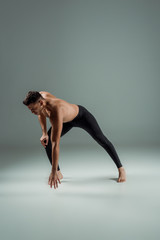 Obraz na płótnie Canvas handsome dancer in black leggings dancing contemporary on dark background