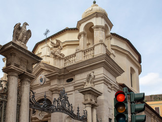 Fototapeta na wymiar A church and traffic lights in a street in Rome