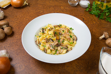 Fettuccine alfredo with mushrooms on an brown table. Selected focus.