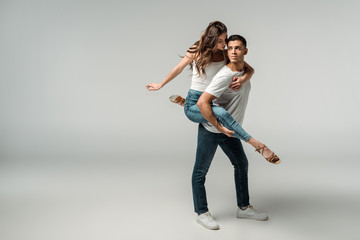 Obraz na płótnie Canvas dancers in denim jeans dancing bachata on grey background